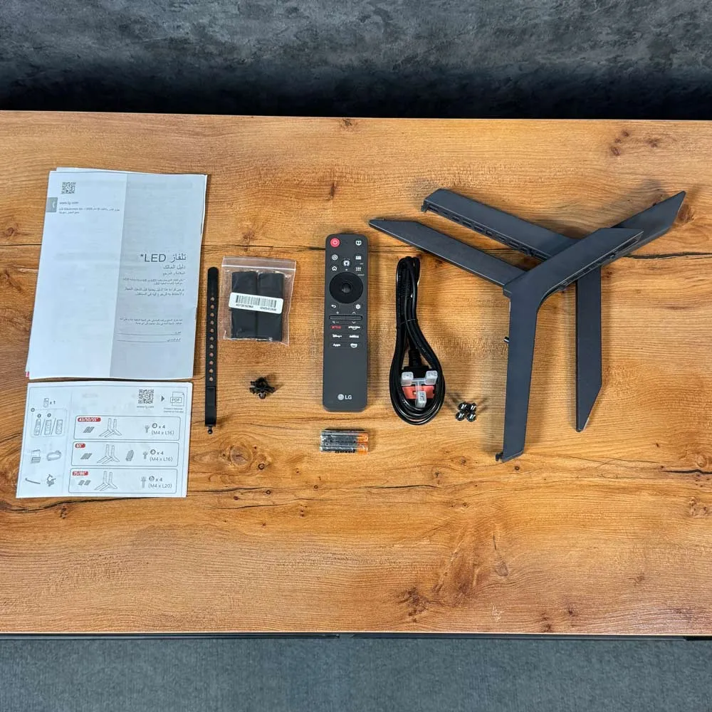 لوازم جانبی تلویزیون ال جی QNED82A شامل ریموت کنترل، پایه، کابل برق و دفترچه راهنما