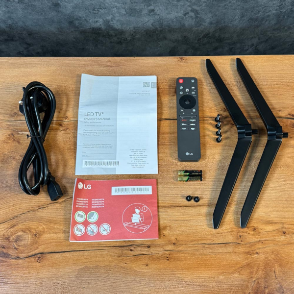 لوازم جانبی تلویزیون ال‌ جی QNED91A شامل پایه‌ها، ریموت، کابل برق و دفترچه راهنما